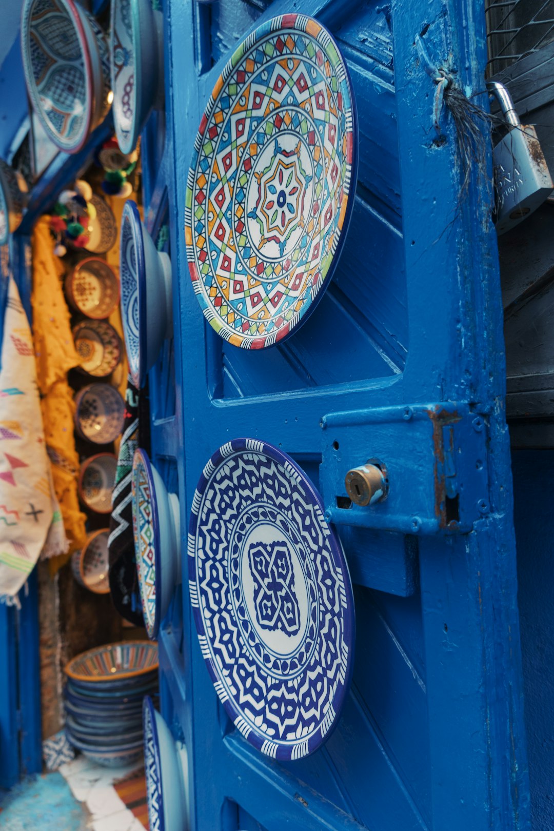 colorful-decorative-plates-displayed-on-a-bright-blue-door-gf221gyc9yg