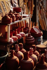 Variety of handcrafted pottery on display at an open-air market, warm earthy tones.