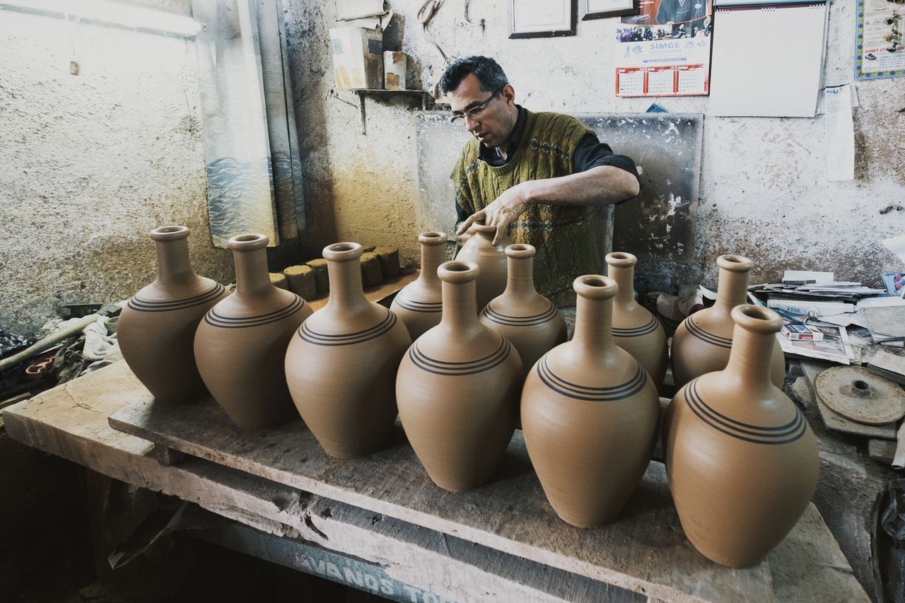 A potter skillfully shaping clay vases in a rustic workshop setting.